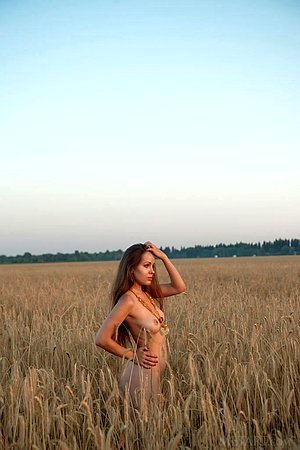 Teaser with a firm booty and big boobs posing in a field seductively