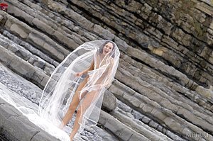 Skinny brunette shows her flexibility while posing by the rocks