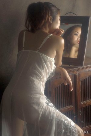 Asian beauty smiles confidently while checking herself out in the mirror