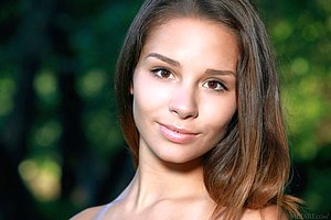 Wonderful teen model takes off her dress to pose naked in the woods