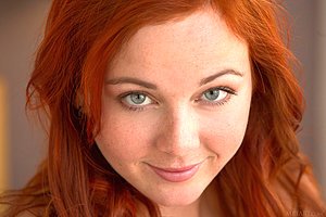 Redheaded babe takes off her black undergarments to pose naked