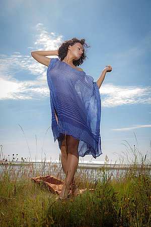 Curly-haired brunette beauty posing in a see-through piece outdoors