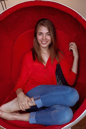 Young beauty with a radiant smile sensually stripping in an egg chair