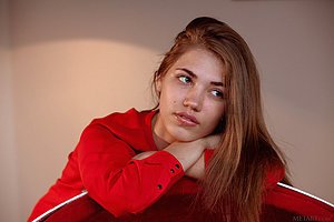 Young beauty with a radiant smile sensually stripping in an egg chair