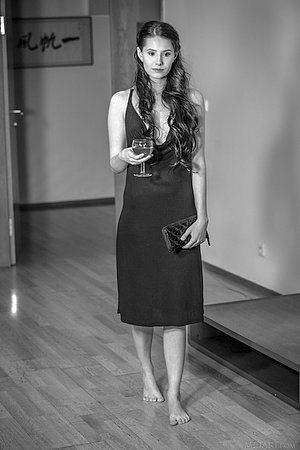 Dress-wearing brunette with weird eyes posing while half-drunk