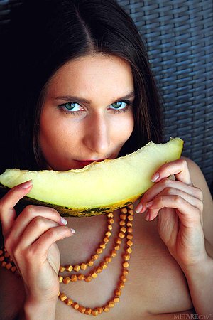 Topless sarong-wearing beauty suggestively fingering the fruit