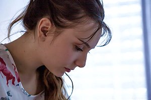 Dark-haired and deeply romantic brunette undressing on a white bed