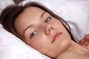 PJs-wearing cute brunette wakes up and sleepily poses naked on a bed