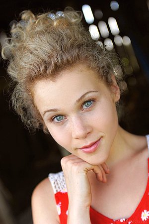 Polka dots top curly-haired blonde poses naked in a wooden barn