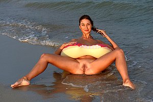 Busty, tanned and toned brunette posing with an inflatable doughnut