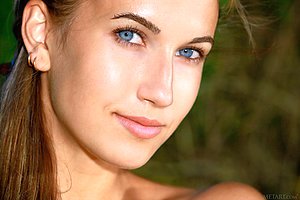 Denim shorts wearing blue-eyed brunette goddess poses next to a lake