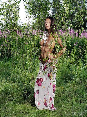 Long-haired brunette in a flowery dress shows her goodies outdoors