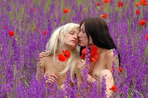 Two half-naked babes posing with each other in a beautiful field